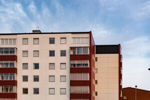 Home Contemporary apartment building facade with multiple windows and balconies against a clear sky.
