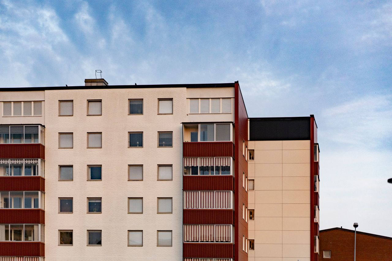 Contemporary apartment building facade with multiple windows and balconies against a clear sky.
