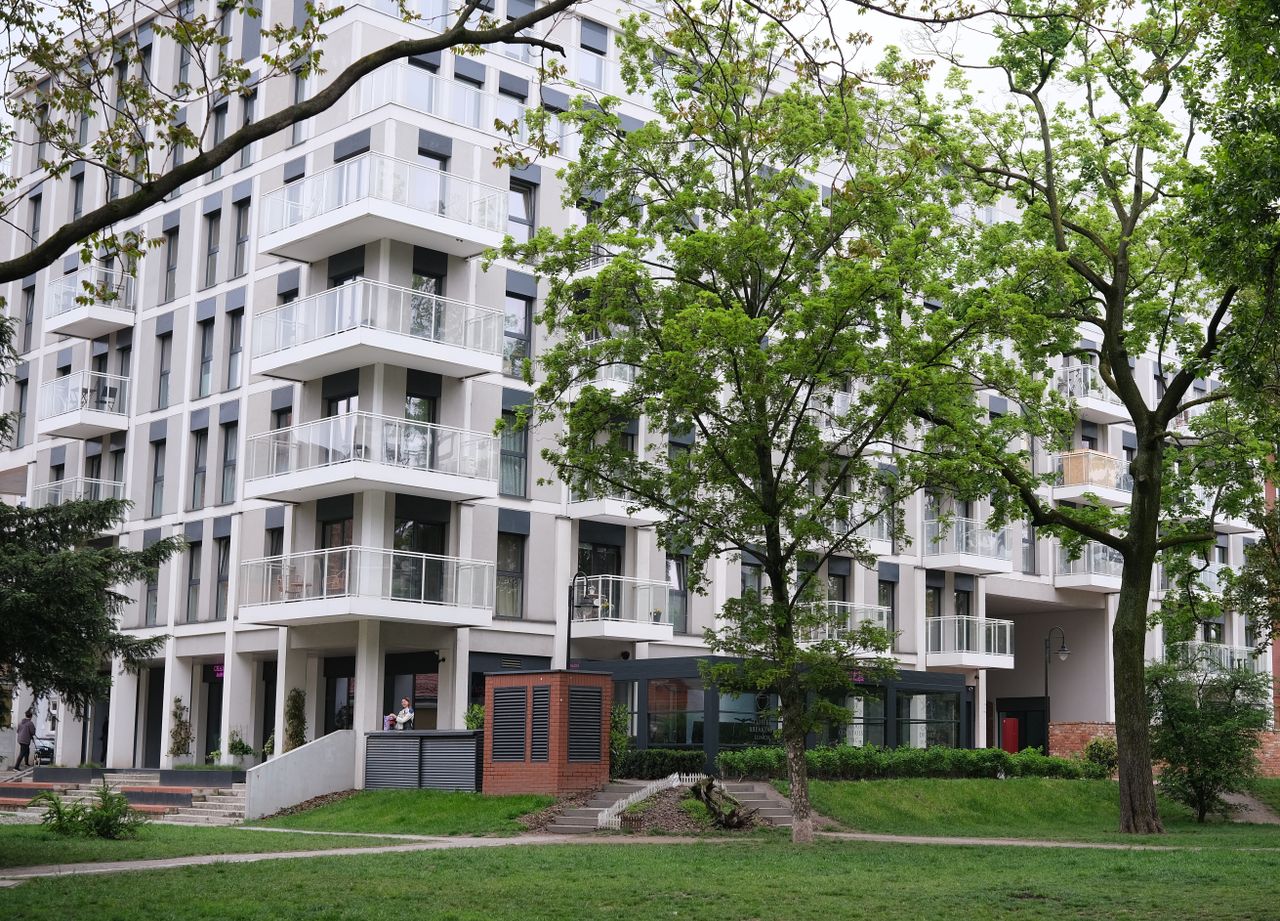 Contemporary urban apartment complex surrounded by lush trees and greenery.
